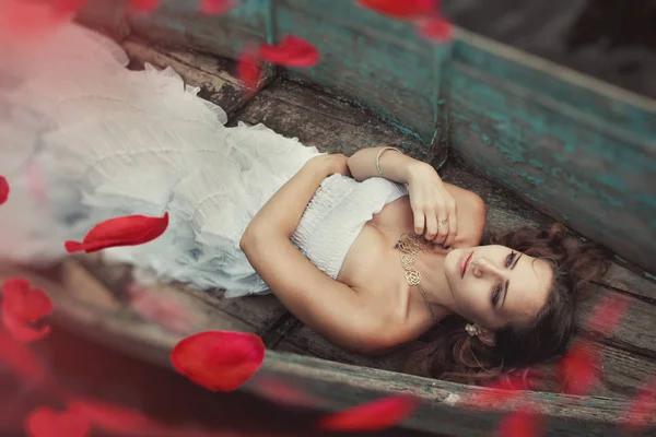 Sonhador misteriosa menina loira em um vestido branco em um velho barco no lago — Fotografia de Stock