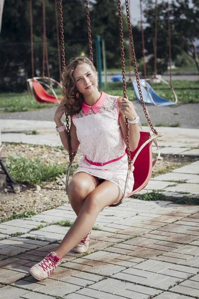 Szép fiatal szőke lány élvezi a nyár a parkban a régi túrák és körhinta — Stock Fotó