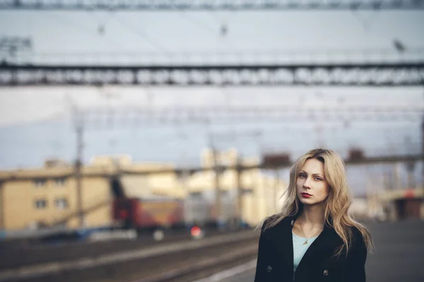 Schöne blonde Mädchen wartet auf den Zug am Bahnhof. romantischer, zarter Look — Stockfoto