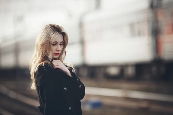 Schöne blonde Mädchen wartet auf den Zug am Bahnhof. romantischer, zarter Look — Stockfoto