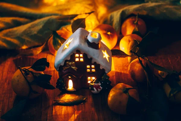 Красиві різдвяні прикраси з мандаринами та іграшковим будинком у нічних легких гірляндах. Цитрусовий натюрморт. Символ нового року — стокове фото