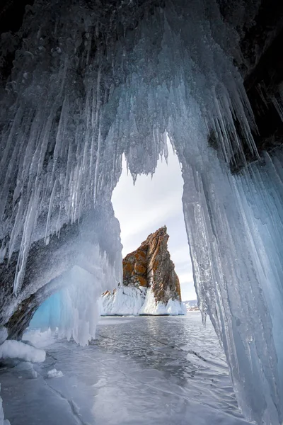 Lake is covered with a thick layer of ice. Ice story. Stone rock sticking out from under the piles of ice. The cleanest lake in the world, lake Baikal — Stock Photo, Image