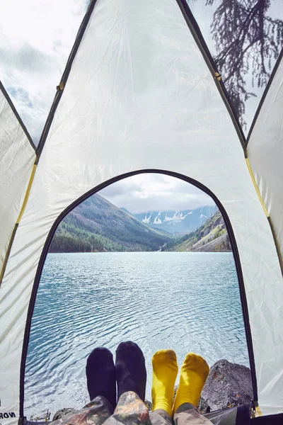 Kvinna och man som ligger i tältet nära sjön med utsikt över snöklädda berg. Vacker soluppgång över sjön — Stockfoto