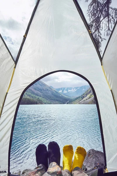 Mujer y hombre acostados en la tienda cerca del lago con vistas a las montañas cubiertas de nieve. Hermoso amanecer sobre el lago — Foto de Stock