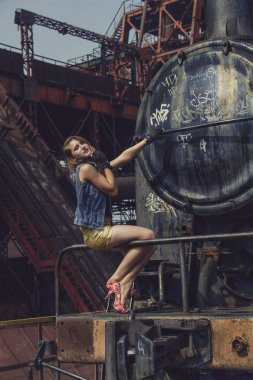 şort ve topuklu bir eski terk edilmiş Fabrikası'nda sarışın seksi kız. Steampunk