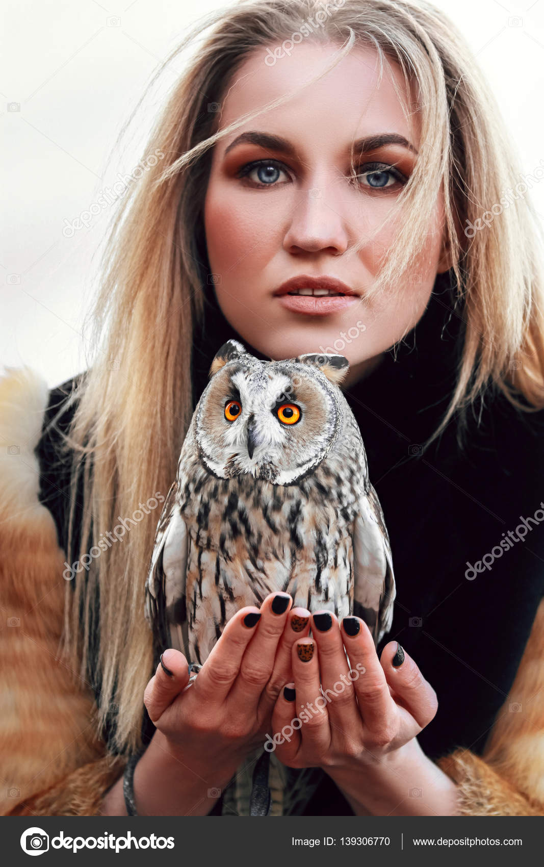 Beautiful woman in a fur coat with an owl on his arm. Blonde with long ...