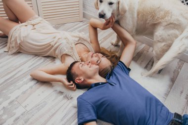 Çift evde köpeğiyle yerde yatıyor. Aşık erkek ve kadın yerde sarılma. Sevgililer günü. Aile mutluluğu