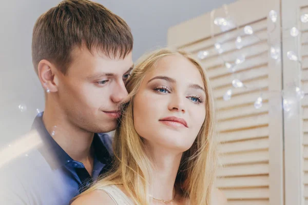 Beautiful loving couple looking out the window. Guy and girl cuddling together. Valentine\'s Day. The reflection in the mirror. Gentle and loving couple