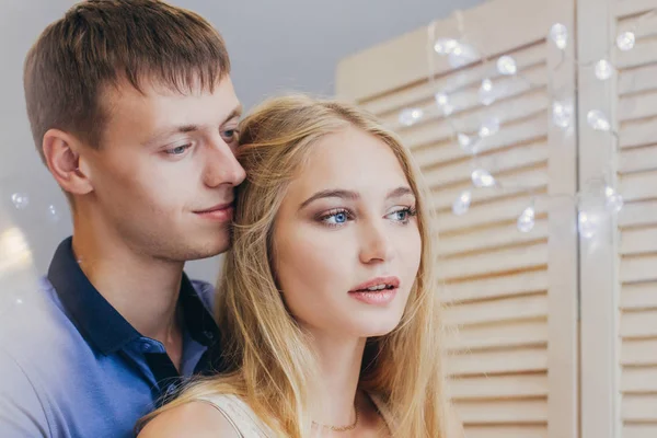 Beautiful loving couple looking out the window. Guy and girl cuddling together. Valentine\'s Day. The reflection in the mirror. Gentle and loving couple