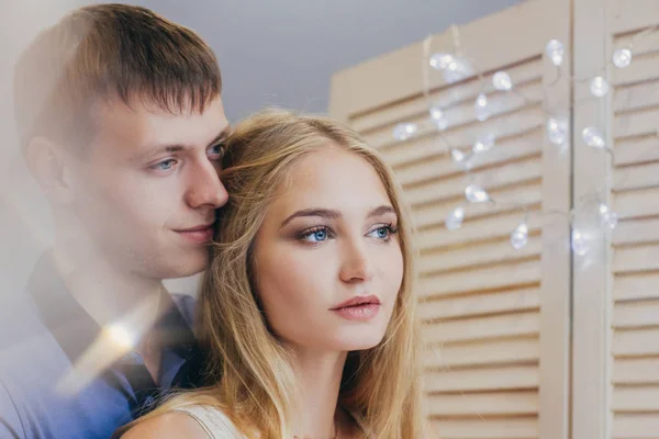 Beautiful loving couple looking out the window. Guy and girl cuddling together. Valentine's Day. The reflection in the mirror. Gentle and loving couple