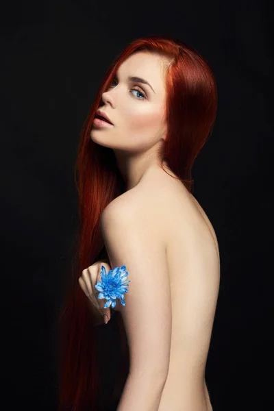 Сексуальная красивая рыжая девушка с длинными волосами. Портрет женщины на черном фоне. Шикарные волосы и глубокие глаза. Естественная красота, чистая кожа, уход за лицом и волосами. Сильные и густые волосы. Цветок — стоковое фото