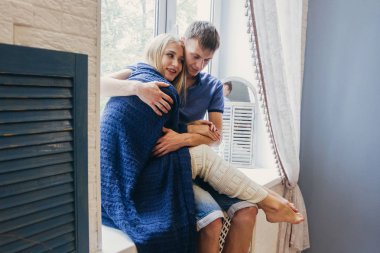 Çift evde oturup cama seviyorum. Yeni evliler ihale sevgi dolu kucaklama. Sevgi dolu bir çift eğlenceli sabah mutlu ruh hali. Kız erkek romantik duygular kucaklamaları. Sevgililer günü