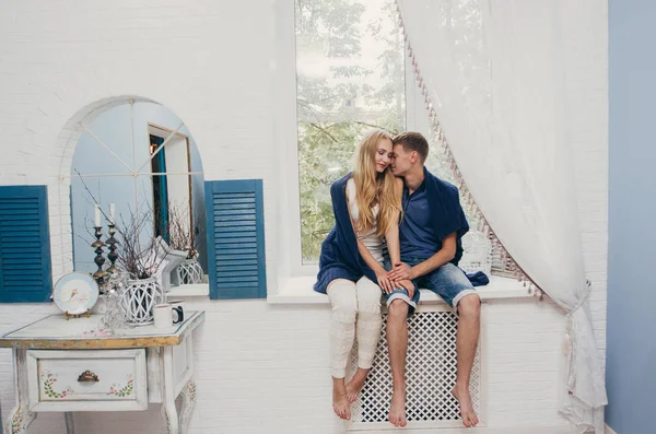 Coppia innamorata seduta a casa alla finestra. Tenero abbraccio amorevole degli sposi novelli. Mattina divertente umore felice di una coppia amorevole. Ragazza coccola fino a fidanzato sentimenti romantici. San Valentino — Foto Stock