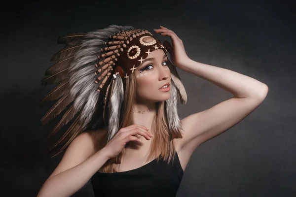 Portrait perfect woman in the garb of American Indians in the smoke on a gray background. Hat made of feathers. Mysterious mystical person, a sexy body, a beautiful face — Stock Photo, Image