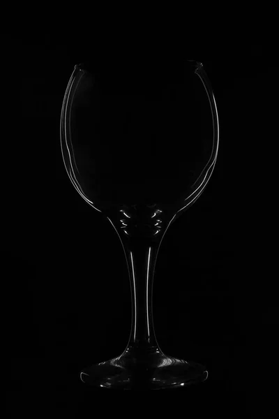 Bokal en verre sur fond noir. Silhouette de verre réfléchit la lumière, photo promotionnelle. Minimalisme laconique, verre photo créatif. Abstraction, contours du verre — Photo