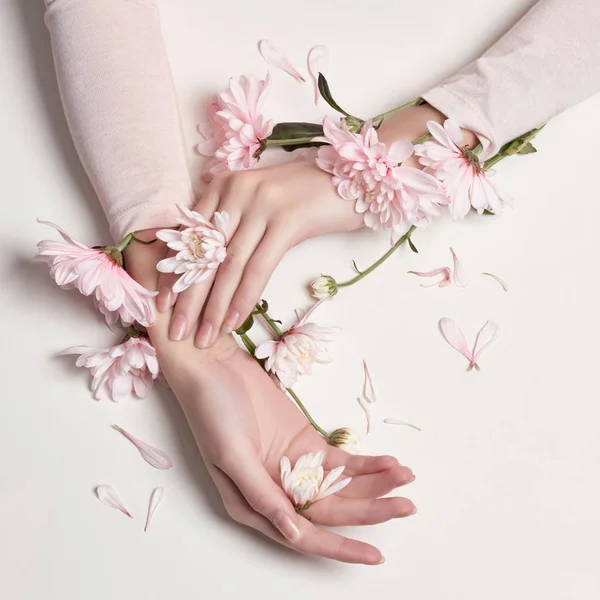 Mode konst stående kvinna i sommarklänning och blommor i sin hand med en ljusa kontrasterande makeup. Kreativa skönhet foto flickor sitter vid bordet på en kontrasterande rosa bakgrund med färgade skuggor. — Stockfoto