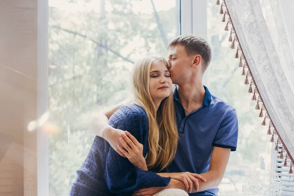 Verliefde paar zittend op het raam, liefdevolle en zachte kijken. Positieve emotie, lachende gezichten. Paar knuffelen en op zoek naar elkaar. Een man en een vrouw liefhebben elkaar. — Stockfoto