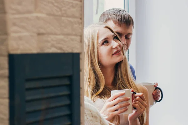 Loving couple sitting on the window, loving and gentle look. Positive emotion, smiling faces. Couple hugging and looking at each other. A man and a woman love each other.