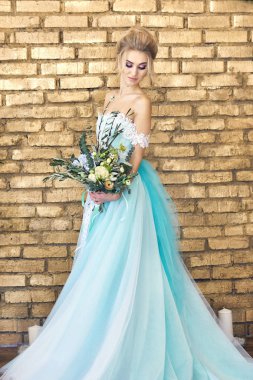 Gelin düğün beklentisiyle turkuaz güzel elbiseli. Dantel elbise deniz yeşil bir buket ile sarışın. Mutlu gelin, duygu, onun yüzünde sevinç. Güzel makyaj, Manikür ve saç modelleri kadınlar.