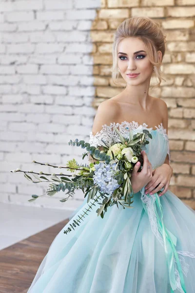 Bruid in een prachtige turquoise jurk in afwachting van de bruiloft. Blonde lace dress zee groen. Gelukkige bruid de emotie de vreugde op zijn gezicht. Mooie make up manicure en kapsel vrouwen. Stock...