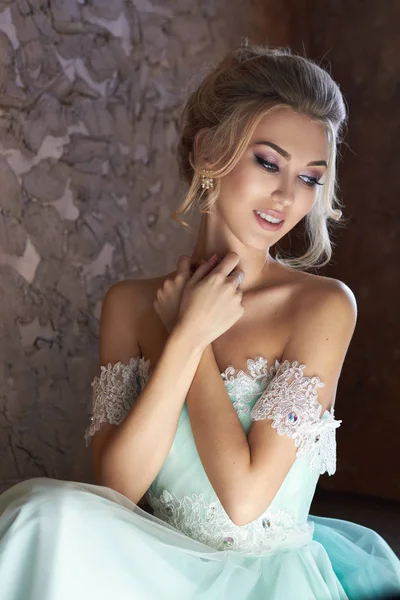 Bride in a beautiful turquoise dress in anticipation of the wedding. Blonde in lace dress sea green. Happy bride, the emotion, the joy on his face. Beautiful makeup manicure and hairstyle women.