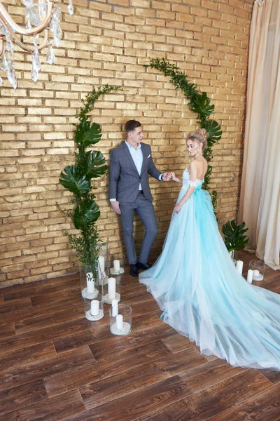 Pareja recién casada, pareja amorosa antes de la boda. Hombre y mujer amándose. La novia en el vestido de turquesa y el novio en un traje azul. Decoración de la boda, zona de fotos de boda —  Fotos de Stock