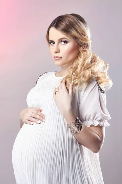 Mujer embarazada en vestido blanco sobre fondo gris. Unos días antes del nacimiento. Hermosa mujer rubia embarazada esperando el nacimiento del niño. Madre embarazada. —  Fotos de Stock