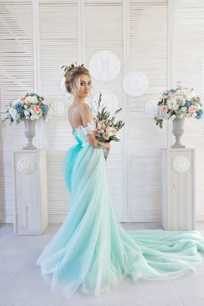 Noiva em um vestido azul-esverdeado bonito em antecipação do casamento. Loira em renda vestido verde mar com um buquê. Noiva feliz, emoção, alegria no rosto. Bela maquiagem, manicuras e penteados mulheres — Fotografia de Stock