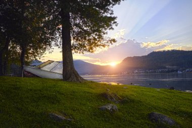 Arka plan açık yaz gün günbatımı gölde tekne. Sıcak yaz akşamı teknenin yanında belgili tanımlık rıhtım. Güneş ışınları gölde muhteşem manzarası.
