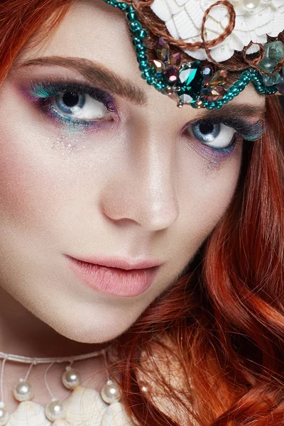 Redhead girl with bright makeup and big lashes. Mysterious fairy woman with red hair. Big eyes and colored shadows, long lashes. Sexy look, pure skin care, care face.