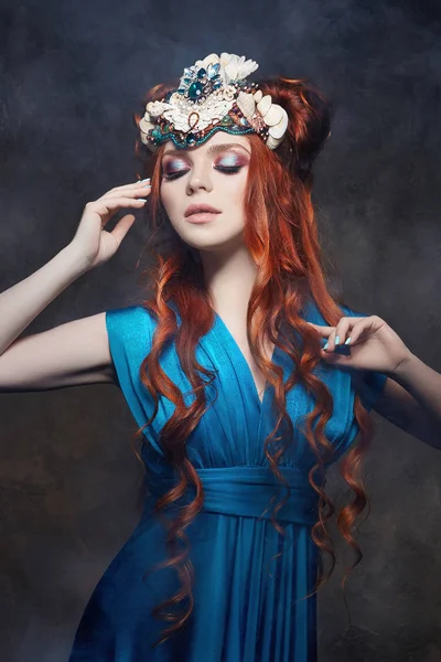 Menina ruiva olhar fabuloso, vestido longo azul, maquiagem brilhante e pestanas grandes. Mulher fada misteriosa com cabelo ruivo. Olhos grandes e sombras coloridas, pestanas longas. Look sexy, Princesa em um fundo escuro . — Fotografia de Stock