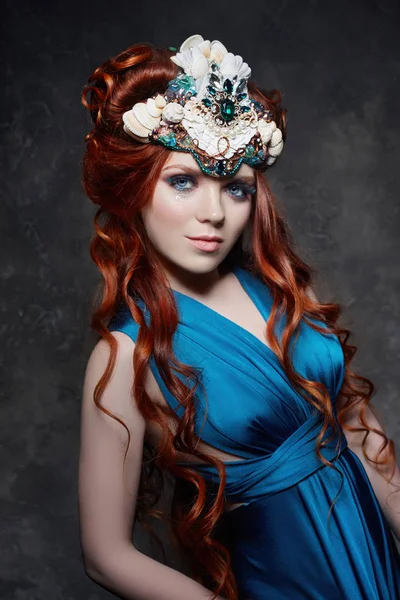 Menina ruiva olhar fabuloso, vestido longo azul, maquiagem brilhante e pestanas grandes. Mulher fada misteriosa com cabelo ruivo. Olhos grandes e sombras coloridas, pestanas longas. Look sexy, Princesa em um fundo escuro . — Fotografia de Stock