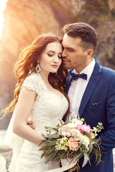 Pareja abrazándose al atardecer, pareja de amantes besándose al atardecer. Ceremonia de boda al aire libre. Hermosos novios con ramo de flores. Vestido de novia blanco para novia. Amor boda pareja abrazo. Borrosa. . —  Fotos de Stock