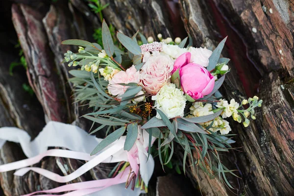 Vacker brudbukett liggande på stenarna. En bukett för flickans bröllopsceremonin. Vackra fina blommor för fest. — Stockfoto