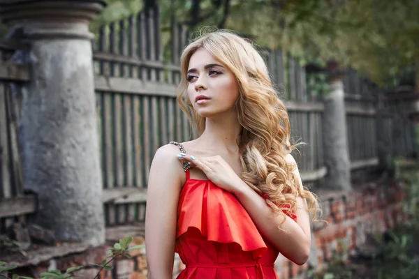 Venkovní módní krásná mladá žena fotky poblíž staré usedlosti léto. Portrét blondýnka dívka v červených šatech. — Stock fotografie