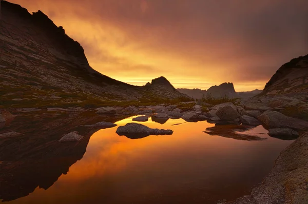 Zachód słońca w górach, w pobliżu jeziora. Światło słoneczne odbite na szczyty gór. Złote światło z nieba odzwierciedlenie w górskim jeziorze. Ergaki — Zdjęcie stockowe