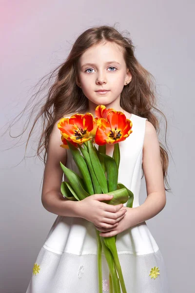 Chica pelirroja de moda con tulipanes en las manos. Foto del estudio sobre fondo de color claro. Cumpleaños, día festivo, día de la madre, primer día de escuela —  Fotos de Stock