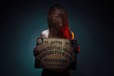 OUIJA Board for divination. Girl holding a OUIJA Board. Woman with long red hair Halloween. Mystic divination conversation with the spirits. clipart