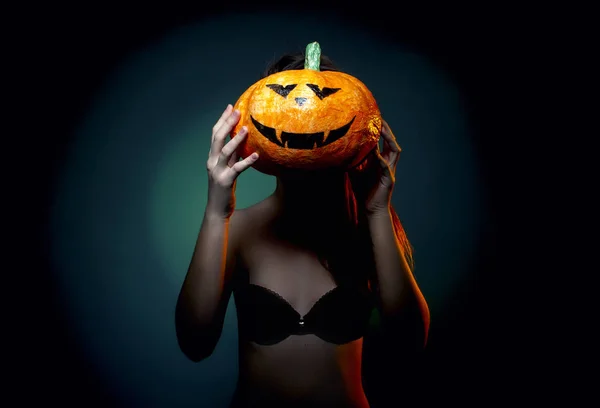 Halloween, donna in mutande con la zucca in mano. Ritratto su sfondo verde scuro . — Foto Stock