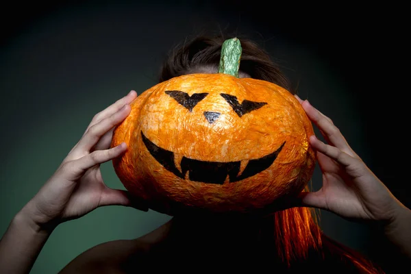 Halloween, mujer en ropa interior con calabaza en sus manos. Retrato sobre fondo verde oscuro . — Foto de Stock