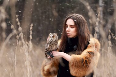 Kadında kürk ceket ile baykuş yandan tarafından ilk sonbahar kar. Güzel esmer baykuş tutan doğada, uzun saçlı. Romantik, hassas göz kızlar