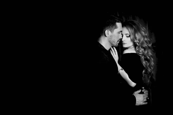 Beau couple amoureux étreignant sur fond noir. Studio photo portrait noir et blanc d'une fille blondes et un gars aux cheveux courts. Saint-Valentin. Un couple marié adoré. Le bonheur familial . — Photo