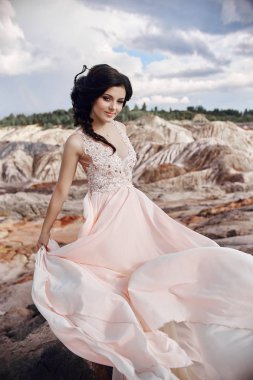 Muhteşem Dağları'nda güzel bir pembe elbiseli kadın. Uzun elbise rüzgârda çırpınıyor. Güzel esmer doğa ile yalnız. Cilt Bakımı, güzel cilt.