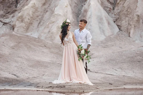 男性の腕の中で花の花束を持つ女性。結婚式の写真撮影自然の中、山々 を背景に新郎新婦、. — ストック写真