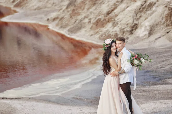 Bride and groom walk along the red mountains, fabulous scene. Couple in love holding hands. Fall wedding outdoors.