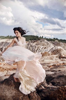 Muhteşem Dağları'nda güzel bir pembe elbiseli kadın. Uzun elbise rüzgârda çırpınıyor. Güzel esmer doğa ile yalnız. Cilt Bakımı, güzel cilt.