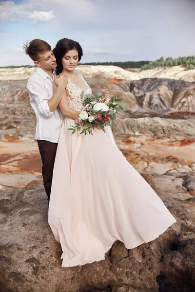 Casal amoroso abraça no fundo das montanhas vermelhas. Amar e cuidar um do outro. Casal amoroso à espera do casamento . — Fotografia de Stock