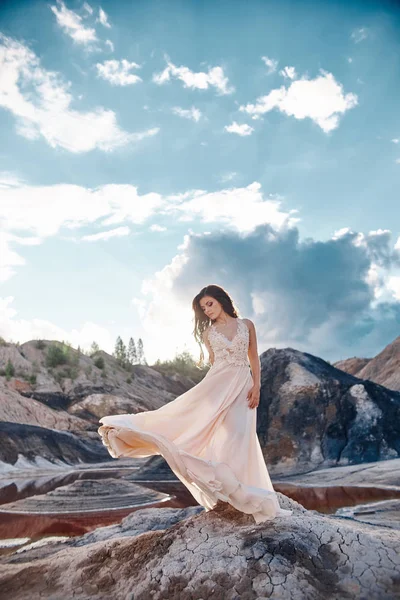 Sexig brunett kvinna i lång klänning stående i vinden på en rygg — Stockfoto
