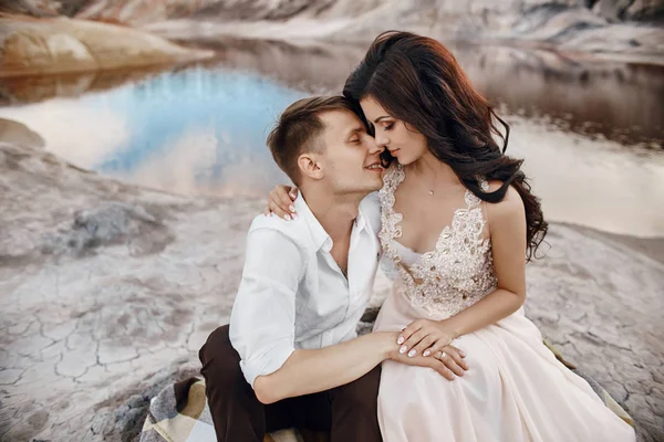 Όμορφο ζευγάρι στην αγάπη φιλί και αγκαλιάζει κάθεται πάνω στον βράχο — Φωτογραφία Αρχείου