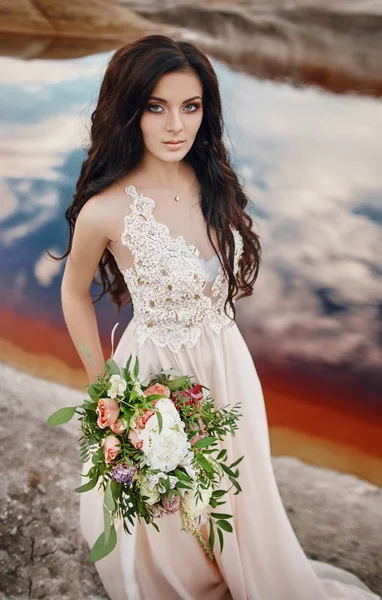 Stående kvinna med blå ögon och blombukett i händerna på naturen. Gorgeous hår och perfekt hud, vacker naturlig makeup. Flicka med en bukett rosor, mystiska dröm bild kvinna. — Stockfoto